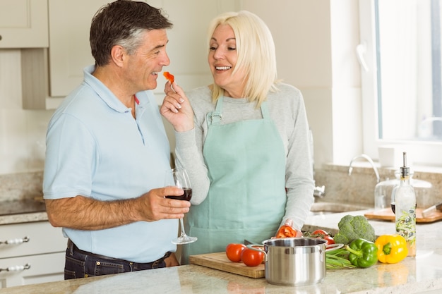 Coppie mature felici che mangiano vino rosso mentre facendo cena