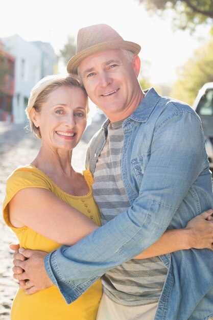 Coppie mature felici che sorridono alla macchina fotografica nella città