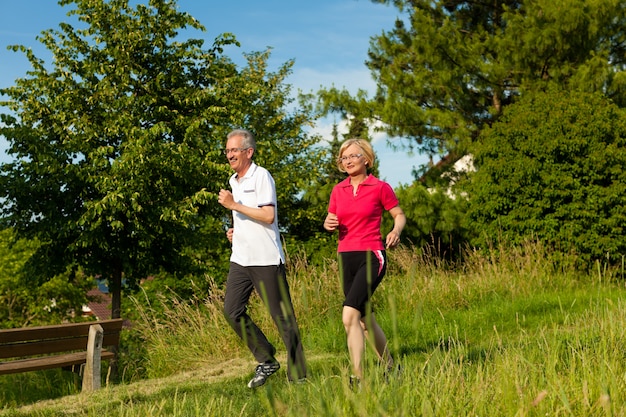 Coppie mature o senior felici che fanno camminare nordico di estate