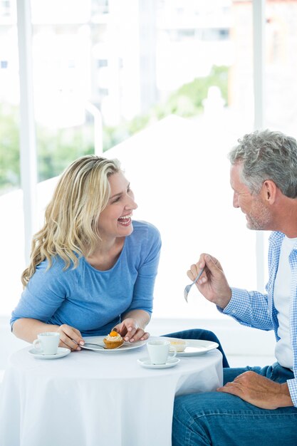 Coppie mature sorridenti che discutono mentre mangiando alimento