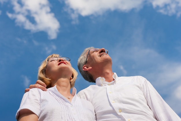 Coppie mature sorridenti che esaminano il cielo blu