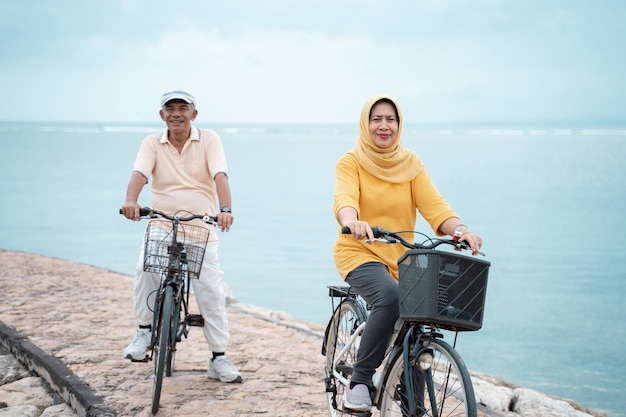 Coppie musulmane senior felici che esercitano insieme la bicicletta di guida