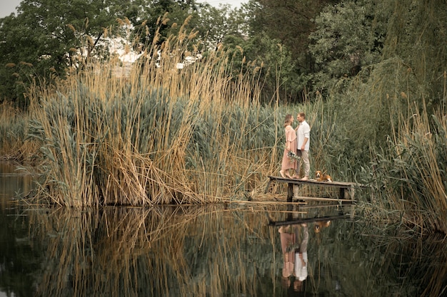 Coppie negli abbracci di amore al pilastro di legno alla natura.