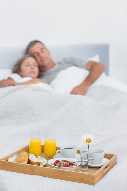 Coppie pacifiche che dormono con il vassoio della prima colazione sul letto