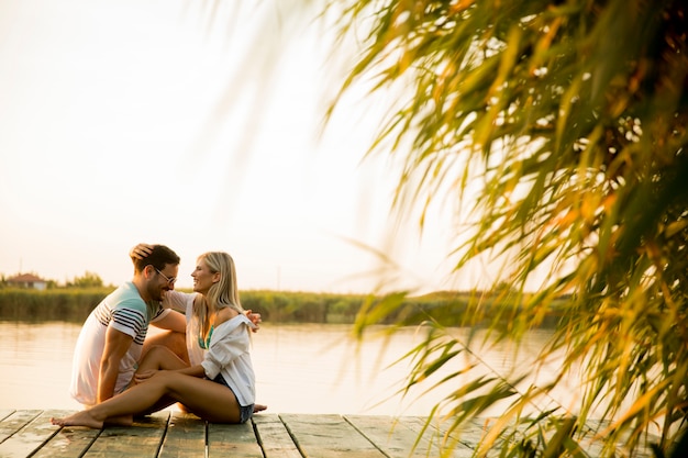 Coppie romantiche che si siedono sul pilastro di legno sul lago