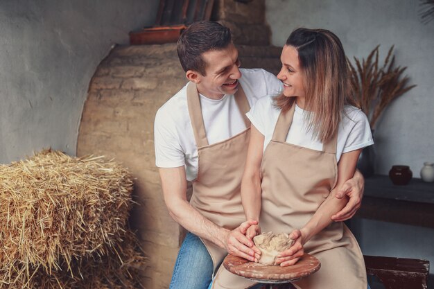 Coppie romantiche nell'amore che lavora insieme sul tornio da vasaio e scolpendo il vaso di terracotta