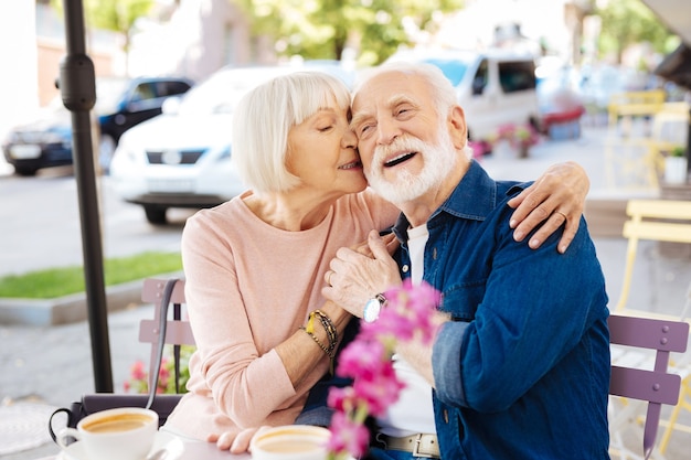 Coppie senior allegre che stringono a sé e che si siedono al caffè