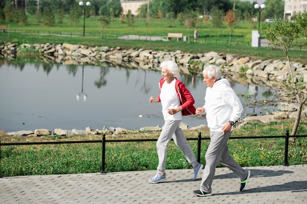 Coppie senior attive che corrono dal lago