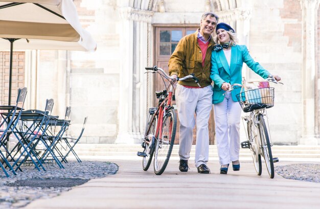 Coppie senior che camminano con la loro bicicletta nel centro urbano