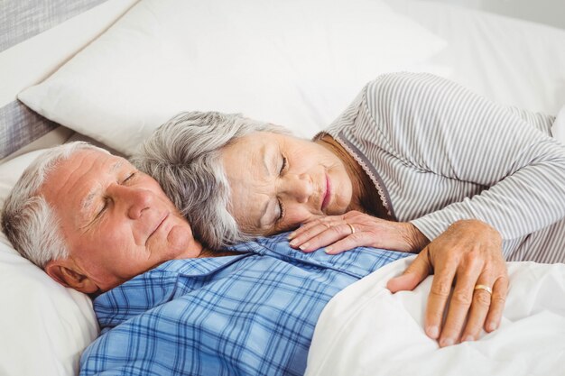 Coppie senior che dormono sul letto in camera da letto