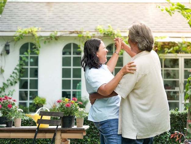 Coppie senior che ridono insieme nel giardino domestico.