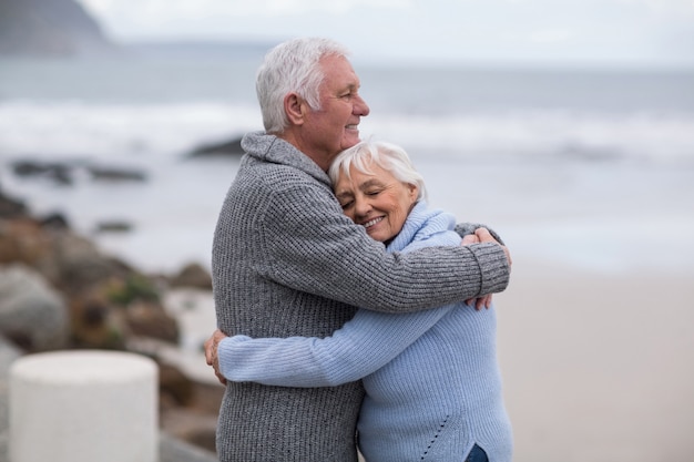 Coppie senior che si abbracciano sulla spiaggia