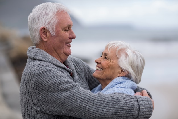 Coppie senior che si abbracciano sulla spiaggia