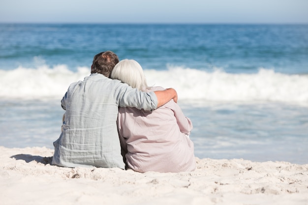 Coppie senior che si siedono sulla spiaggia