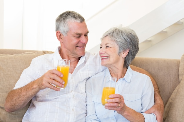 Coppie senior che si siedono sullo strato che beve il succo di arancia