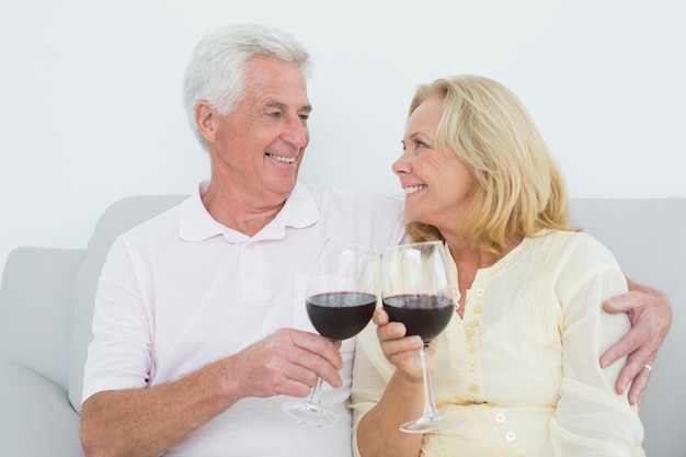 Coppie senior che tostano i vetri di vino