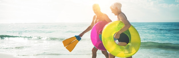 Coppie senior felici che camminano sulla spiaggia