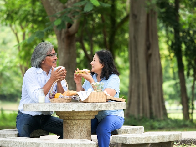 Coppie senior felici che fanno un picnic nella casa del giardino.