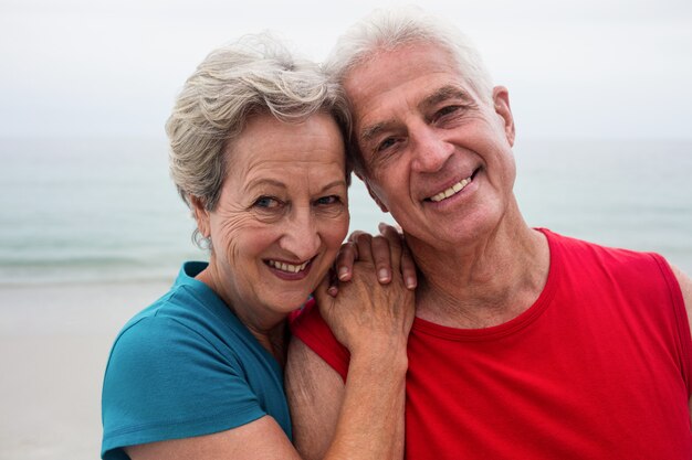 Coppie senior felici che si abbracciano sulla spiaggia