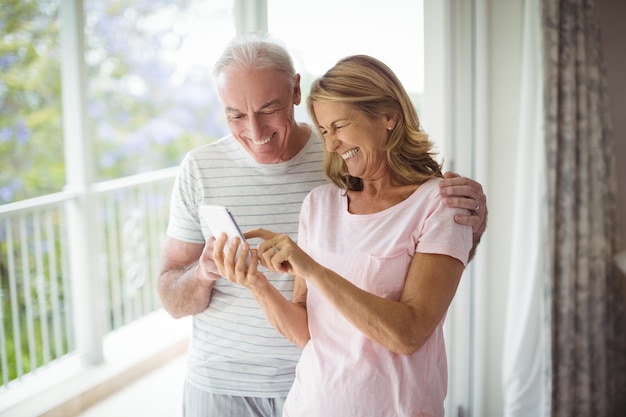 Coppie senior felici che utilizzano telefono cellulare nel balcone