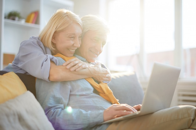 Coppie senior felici facendo uso del computer portatile al sole