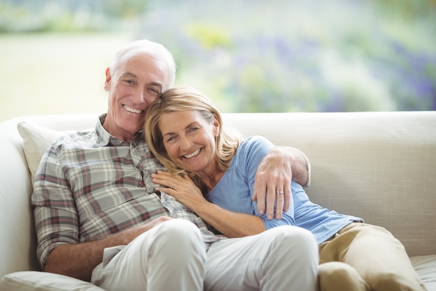 Coppie senior sorridenti che si siedono insieme sul sofà in salone