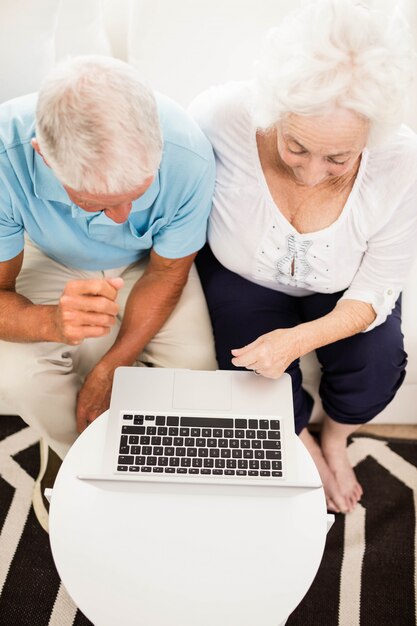 Coppie senior sorridenti facendo uso del computer portatile a casa