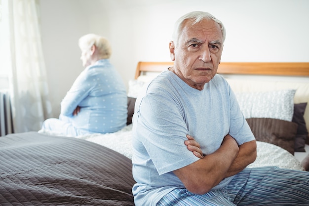 Coppie senior tristi che si siedono sul letto