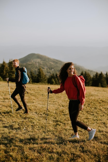 Coppie sorridenti che camminano con gli zainhi sopra le colline verdi