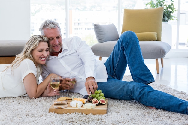 Coppie sorridenti che mangiano alimento mentre trovandosi sulla coperta