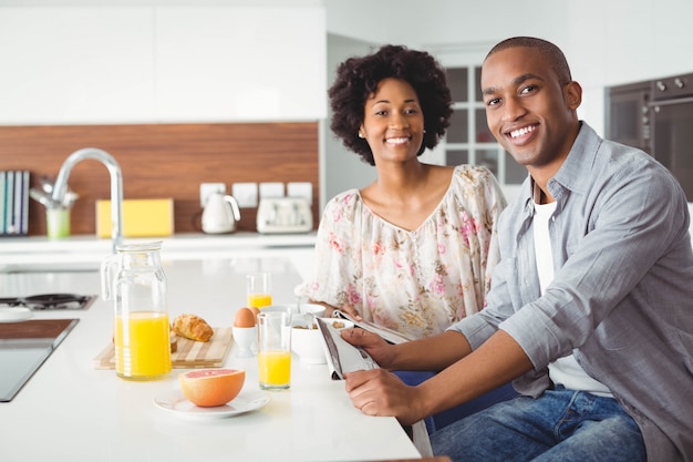 Coppie sorridenti che mangiano insieme prima colazione nella cucina a casa