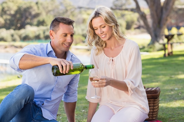 Coppie sorridenti che si siedono e che versano vino in vetro