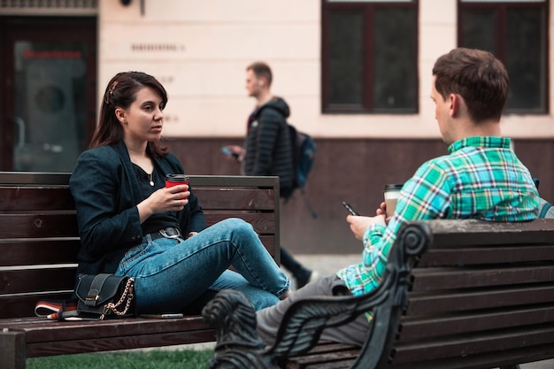 Coppie sorridenti che si siedono sulla panchina che parlano tra loro a bere caffè