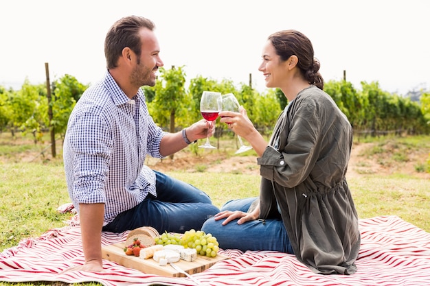 Coppie sorridenti che tostano i bicchieri di vino rossi