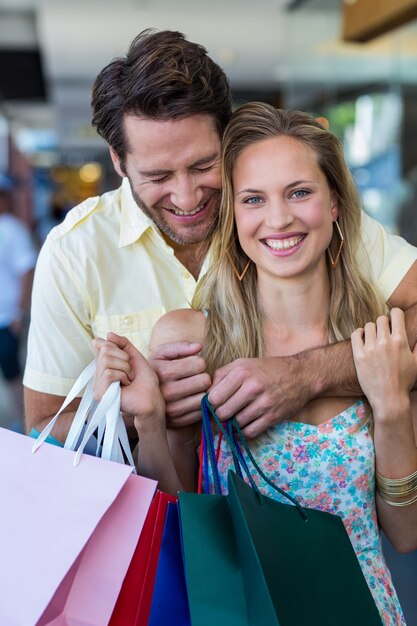 Coppie sorridenti con l&#39;abbraccio dei sacchetti della spesa