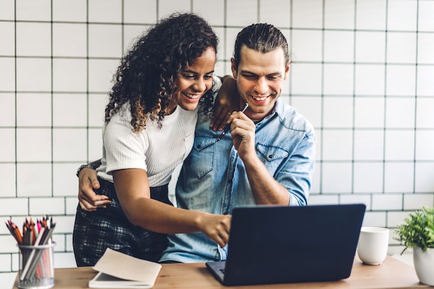 Coppie sorridenti felici che lavorano con il computer portatile