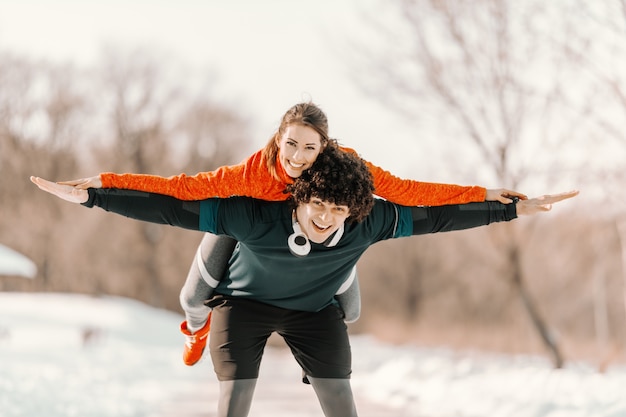 Coppie sportive sorridenti felici che hanno sulle spalle nella natura. Concetto di fitness invernale.