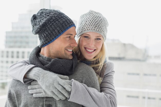 Coppie sveglie in vestiti caldi che abbracciano donna che sorride alla macchina fotografica