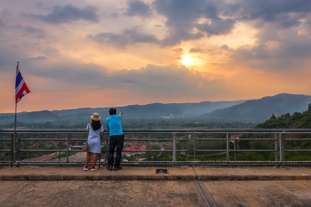 Coppie turistiche di con grande vista in vista del fiume e le montagne sulla diga di Khun Dan Prakan Chon