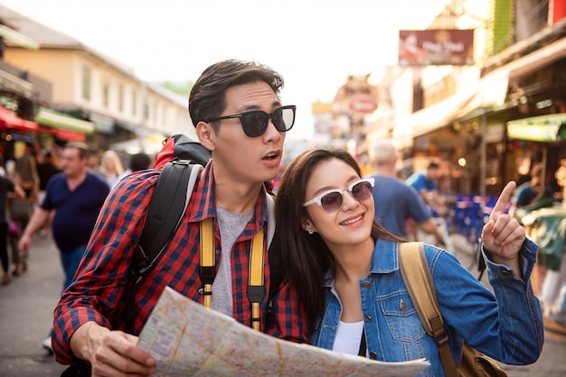 Coppie turistiche facendo uso della mappa mentre viaggiando nella strada Bangkok Tailandia di Khao San