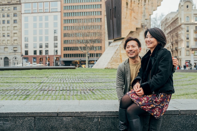 Coppie turistiche felici asiatiche che si siedono sul giro