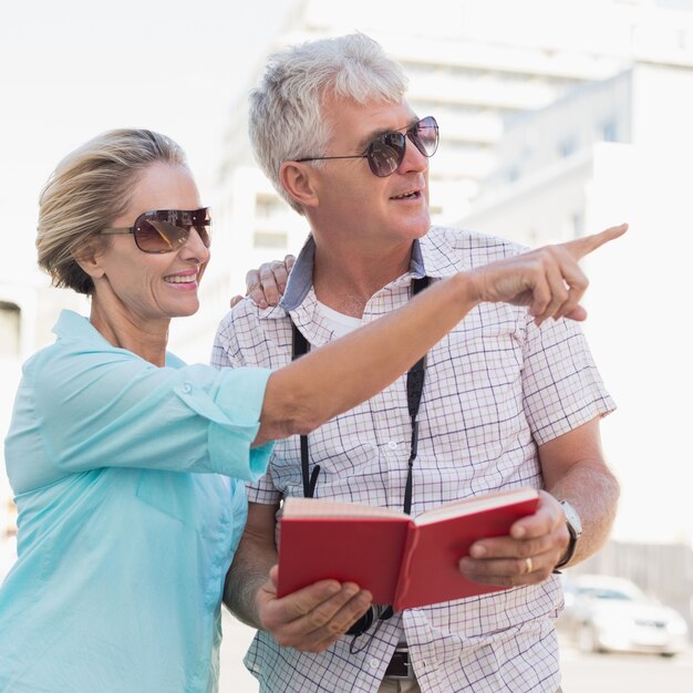 Coppie turistiche felici facendo uso della guida turistica nella città