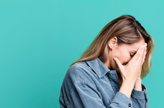 Coprendo gli occhi con le mani con uno sguardo triste e frustrato di disperazione che piange vista laterale