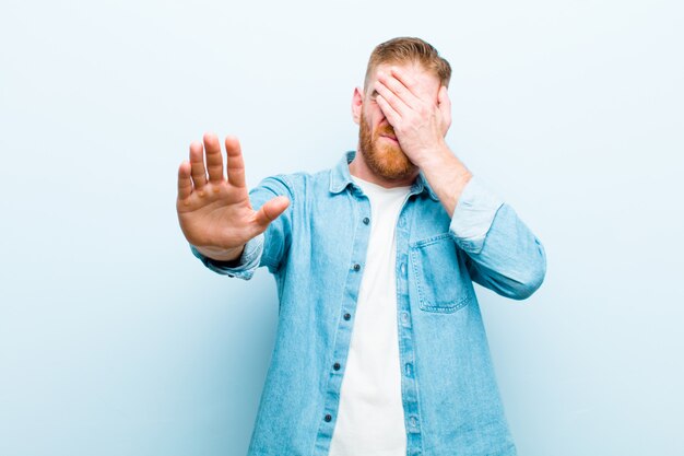 coprendo il viso con la mano e mettendo l'altra mano in avanti per fermare la fotocamera, rifiutando foto o immagini