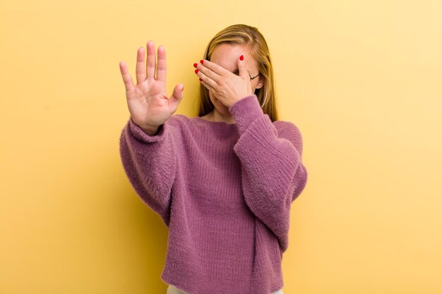 coprendo il viso con la mano e mettendo l'altra mano in avanti per impedire alla fotocamera di rifiutare foto o immagini