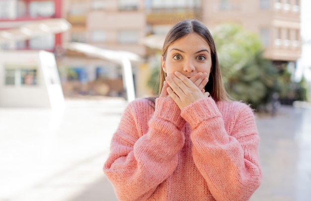 coprendo la bocca con le mani con un'espressione scioccata e sorpresa mantenendo un segreto o dicendo oops