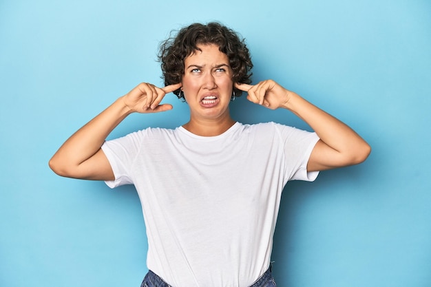 Coprire le orecchie con le dita stressate e disperate da un ambiente rumoroso