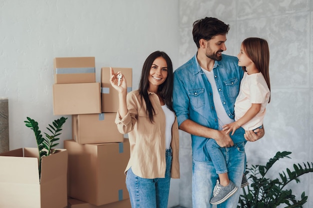 Copyspace foto di una giovane donna contenta che mostra le chiavi della nuova casa mentre suo marito tiene in braccio il loro adorabile bambino