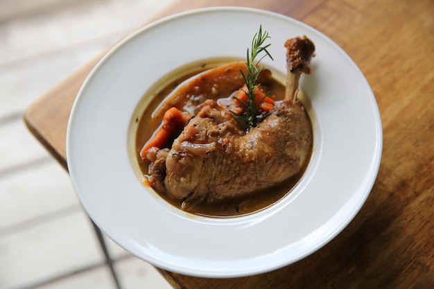 Coq au vin, pollo stufato al vino rosso con carote e patate su fondo di legno, cibi francesi