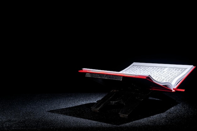 Corano aperto su una tovaglietta in legno con sfondo scuro